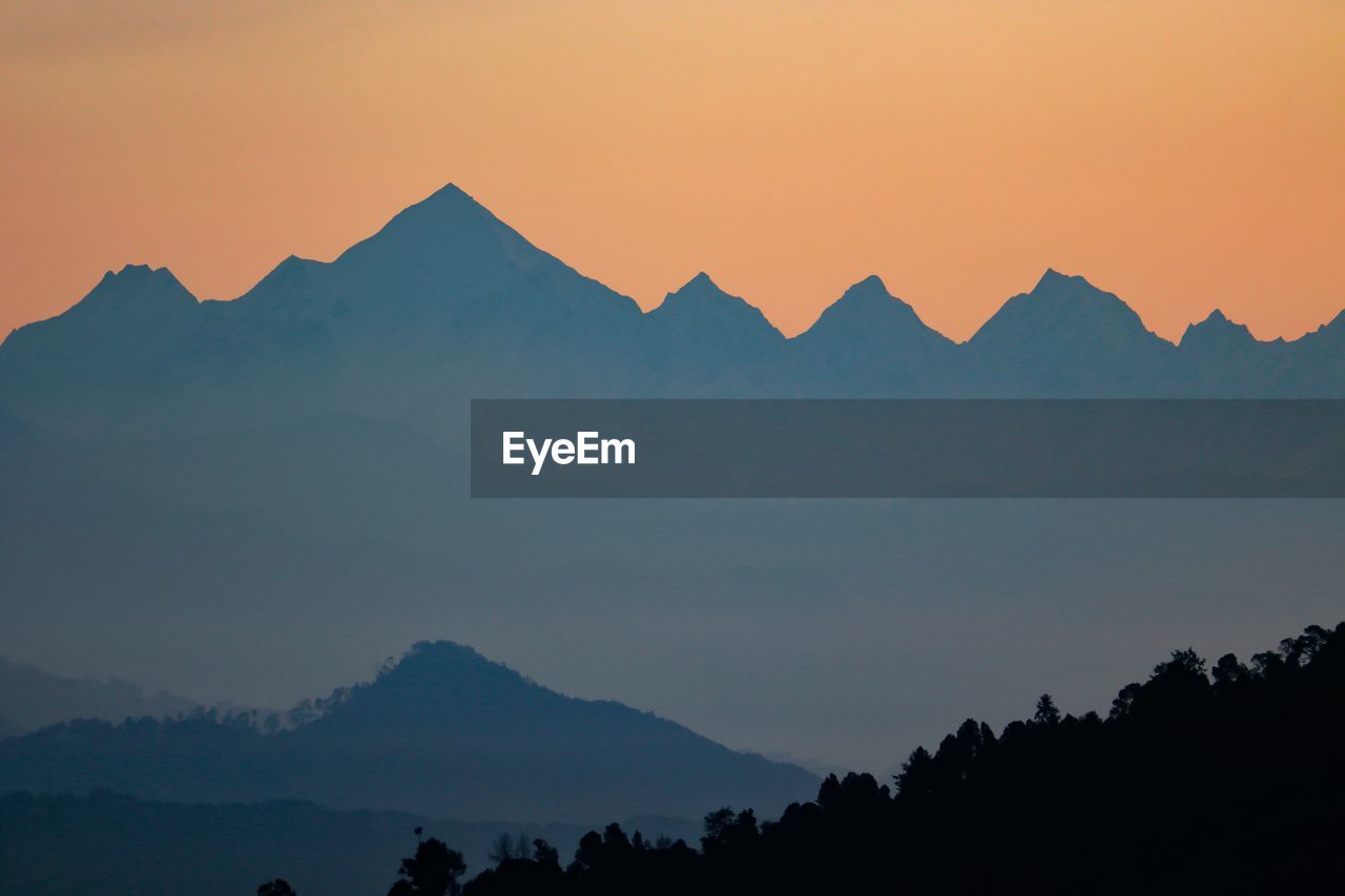 Scenic view of silhouette mountains against orange sky