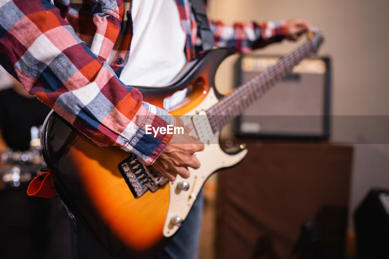 Midsection of man playing guitar