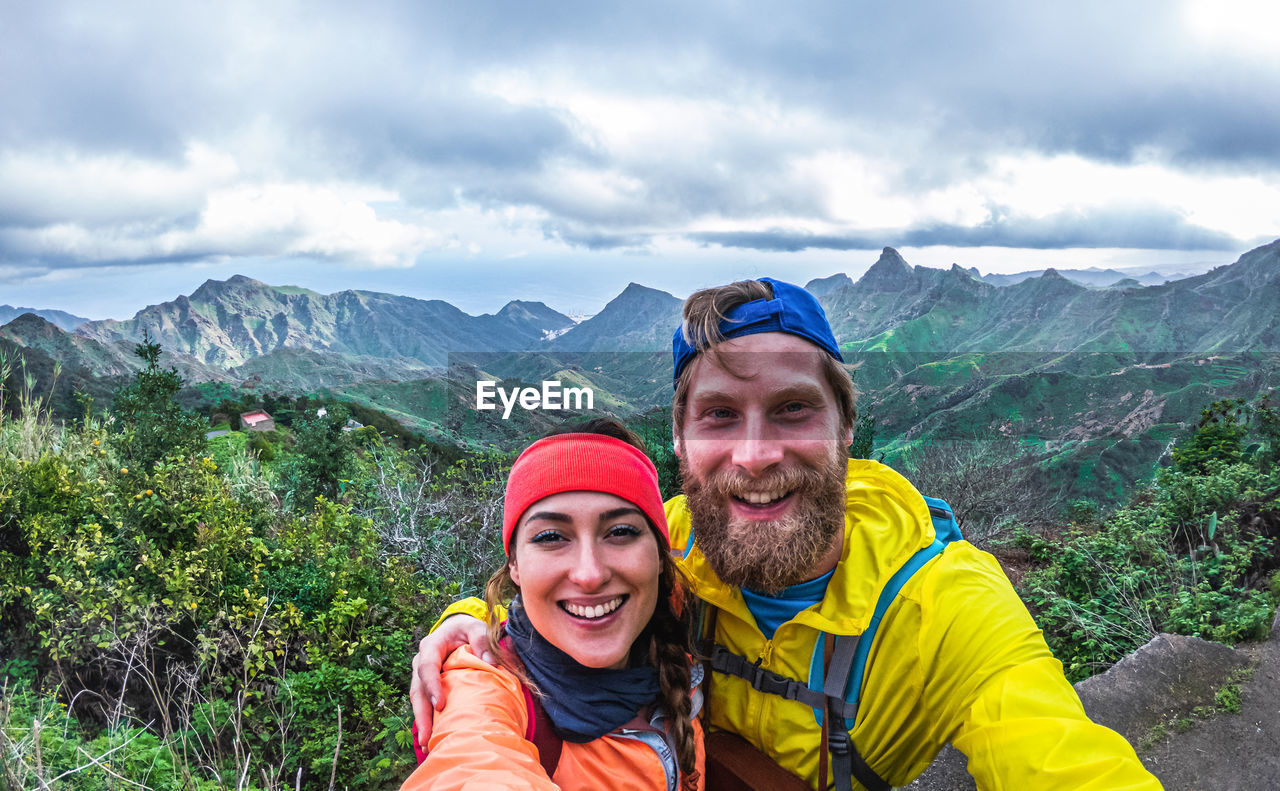 Portrait of happy friends against mountains