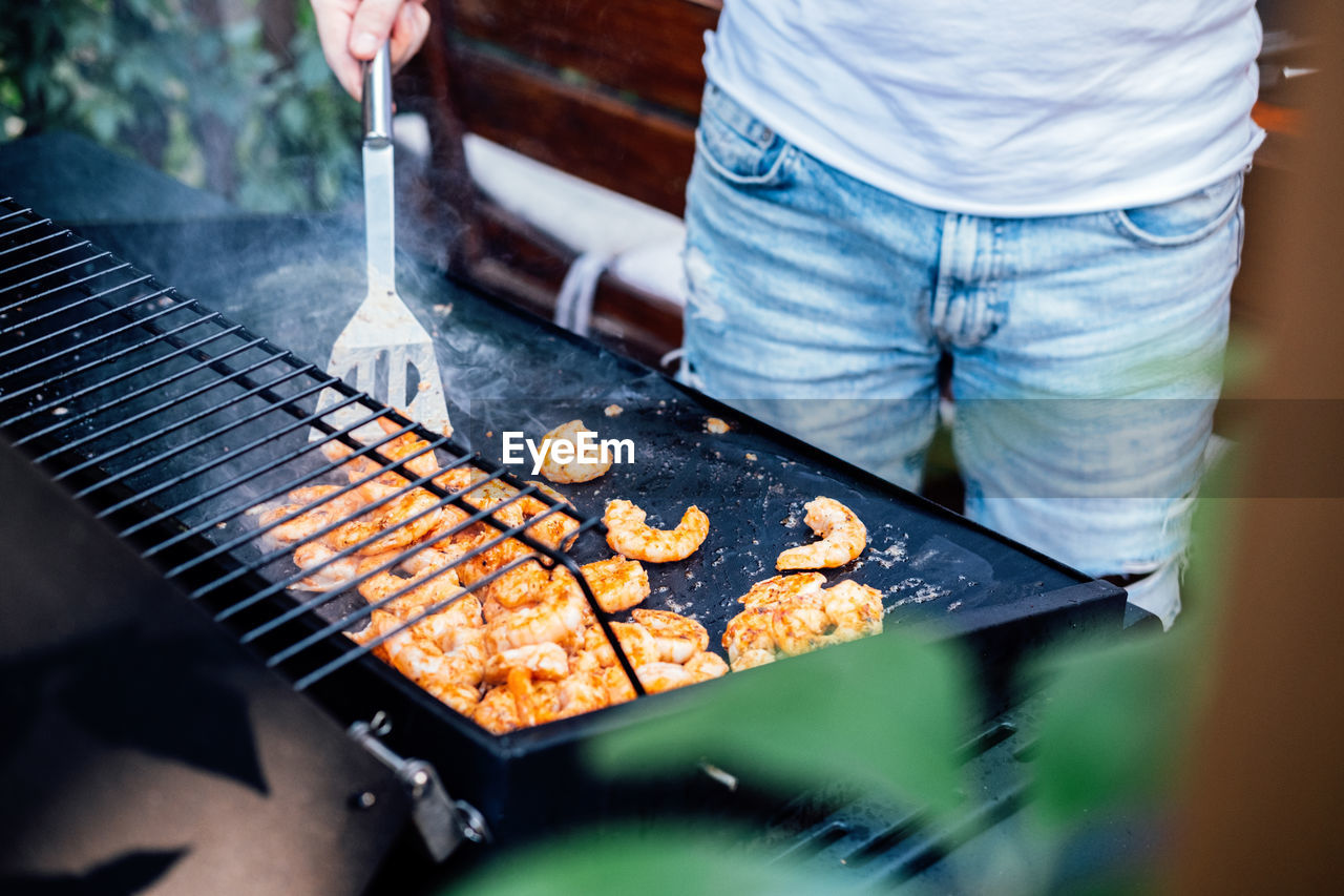 Grilling shrimp on skewer on outdoor grill. grilled shrimps on the flaming grill. man hand using