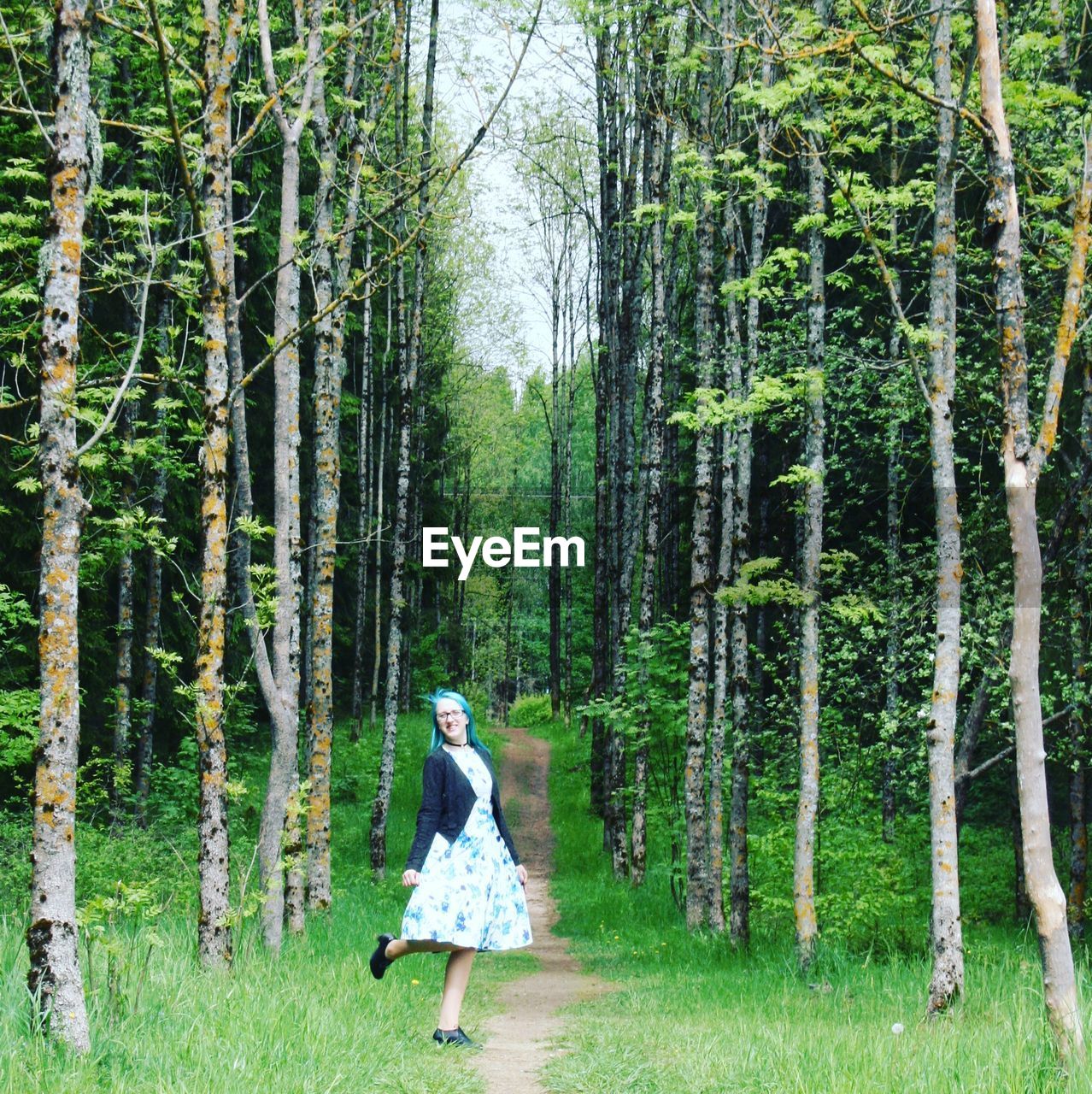 Young woman standing amidst trees at forest