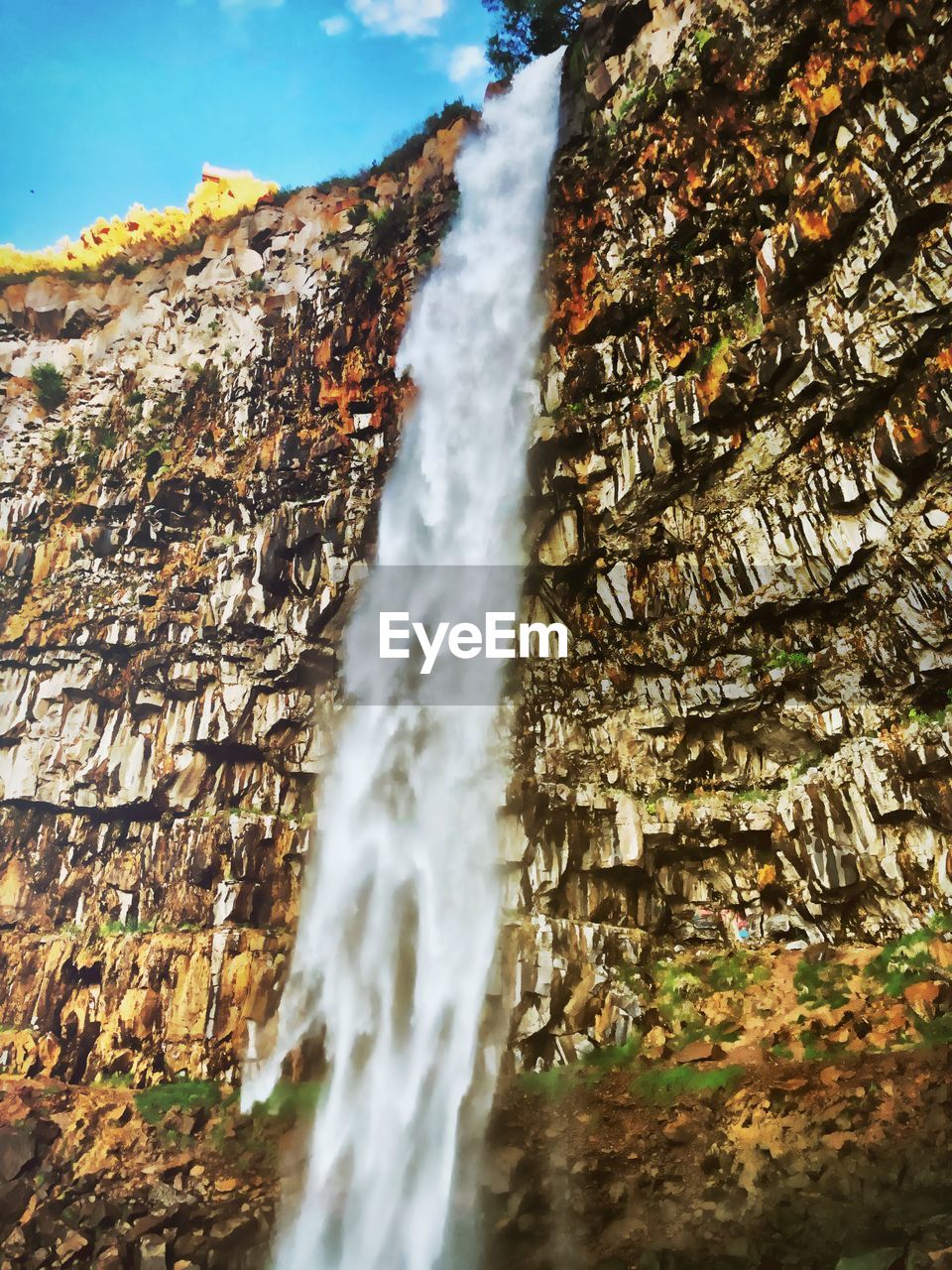 LOW ANGLE VIEW OF WATERFALL AGAINST ROCKS