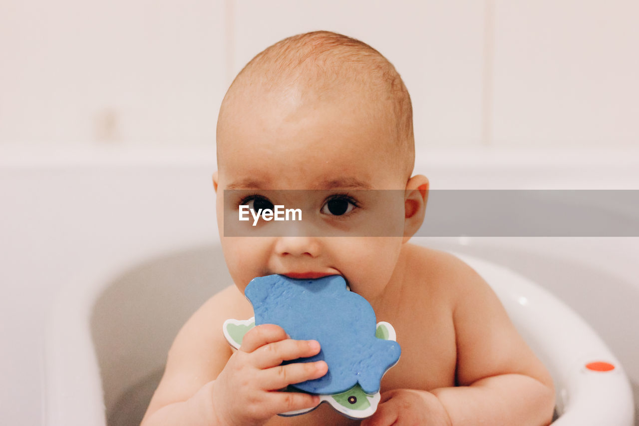 Sweet funny baby taking a bath. baby chewing a toy in a bath chair.