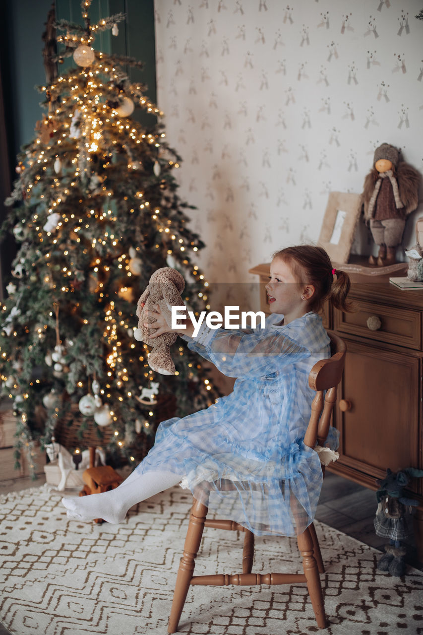 young woman sitting on christmas tree at home