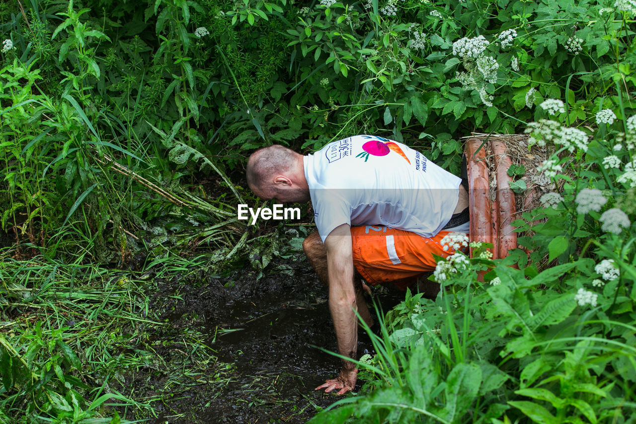 MAN WORKING BY PLANTS IN FIELD