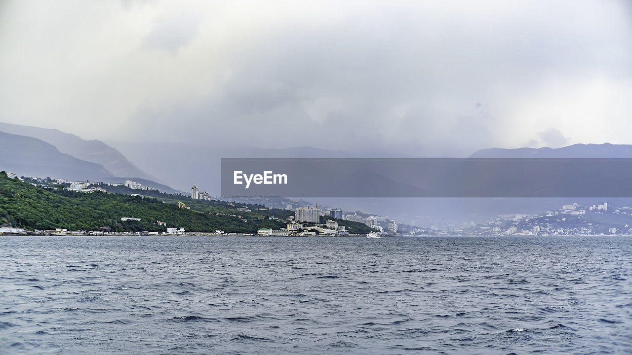 PANORAMIC VIEW OF SEA BY BUILDINGS AGAINST SKY