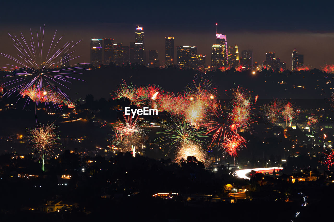 Firework display in city against sky at night