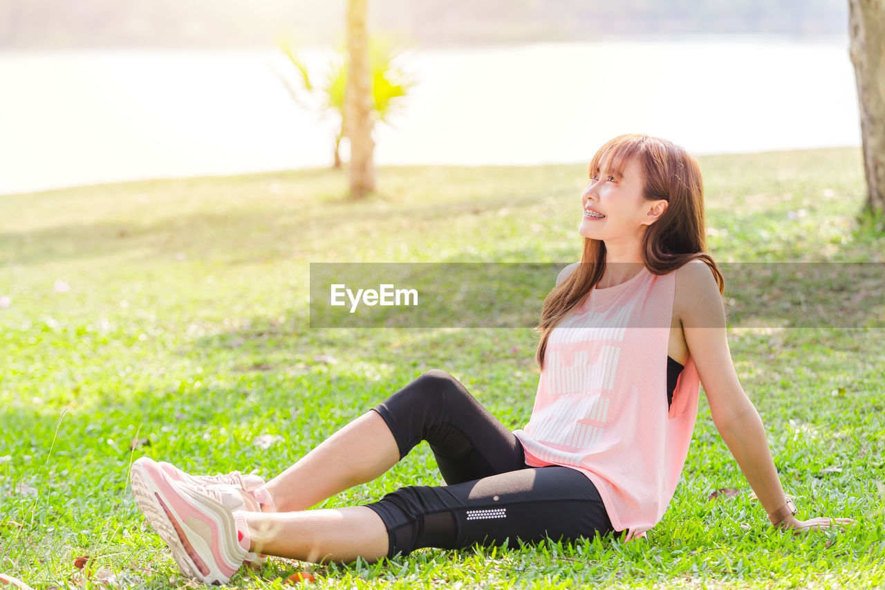 Side view of woman looking away while sitting on grass