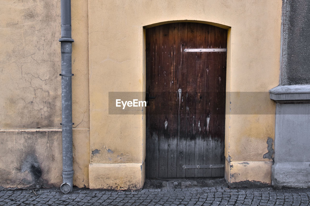 architecture, door, entrance, building exterior, built structure, closed, wall, building, blue, no people, day, city, security, urban area, protection, wall - building feature, old, house, wood, facade, street, outdoors, window, doorway, residential district, iron, road, front door
