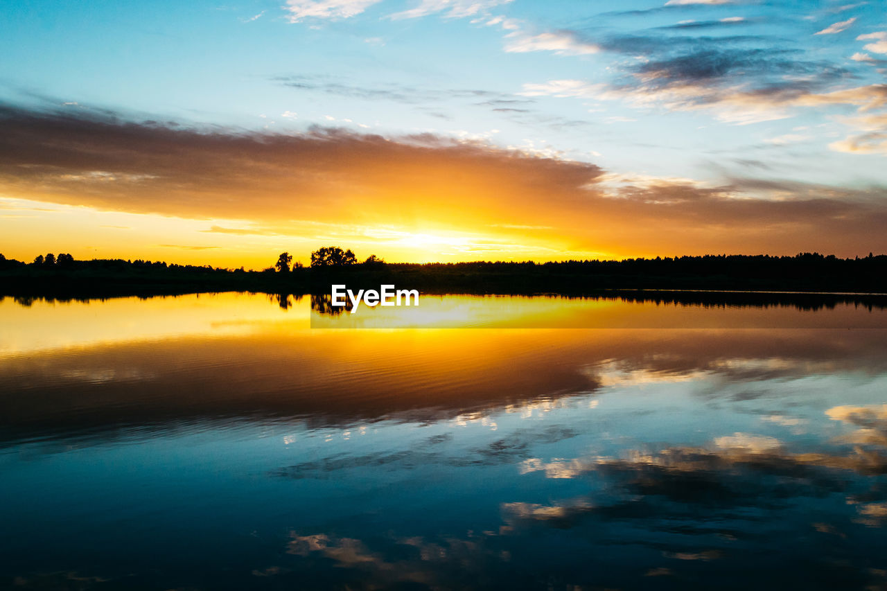 Summer sunset on the lake with a mirror reflection of the sky