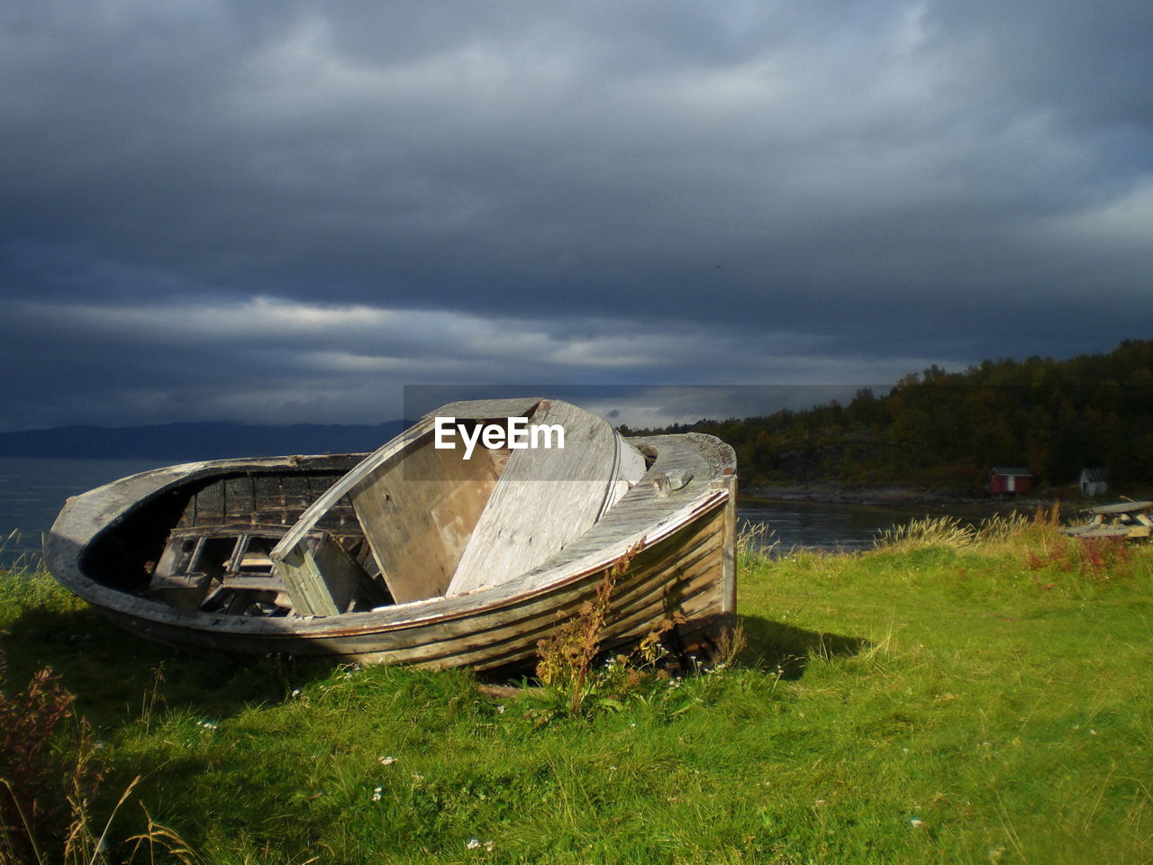 Abandoned boat on field against sky