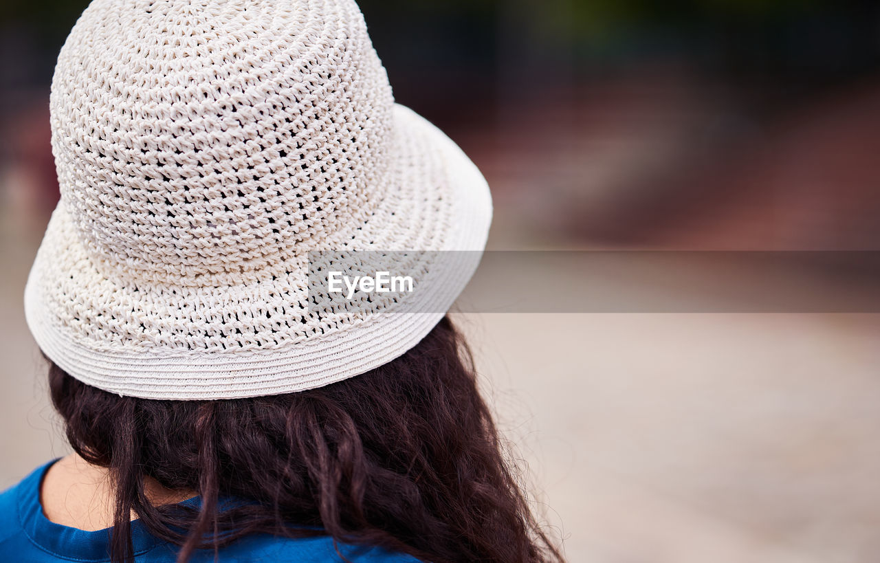 REAR VIEW OF WOMAN WEARING HAT ON ROCK