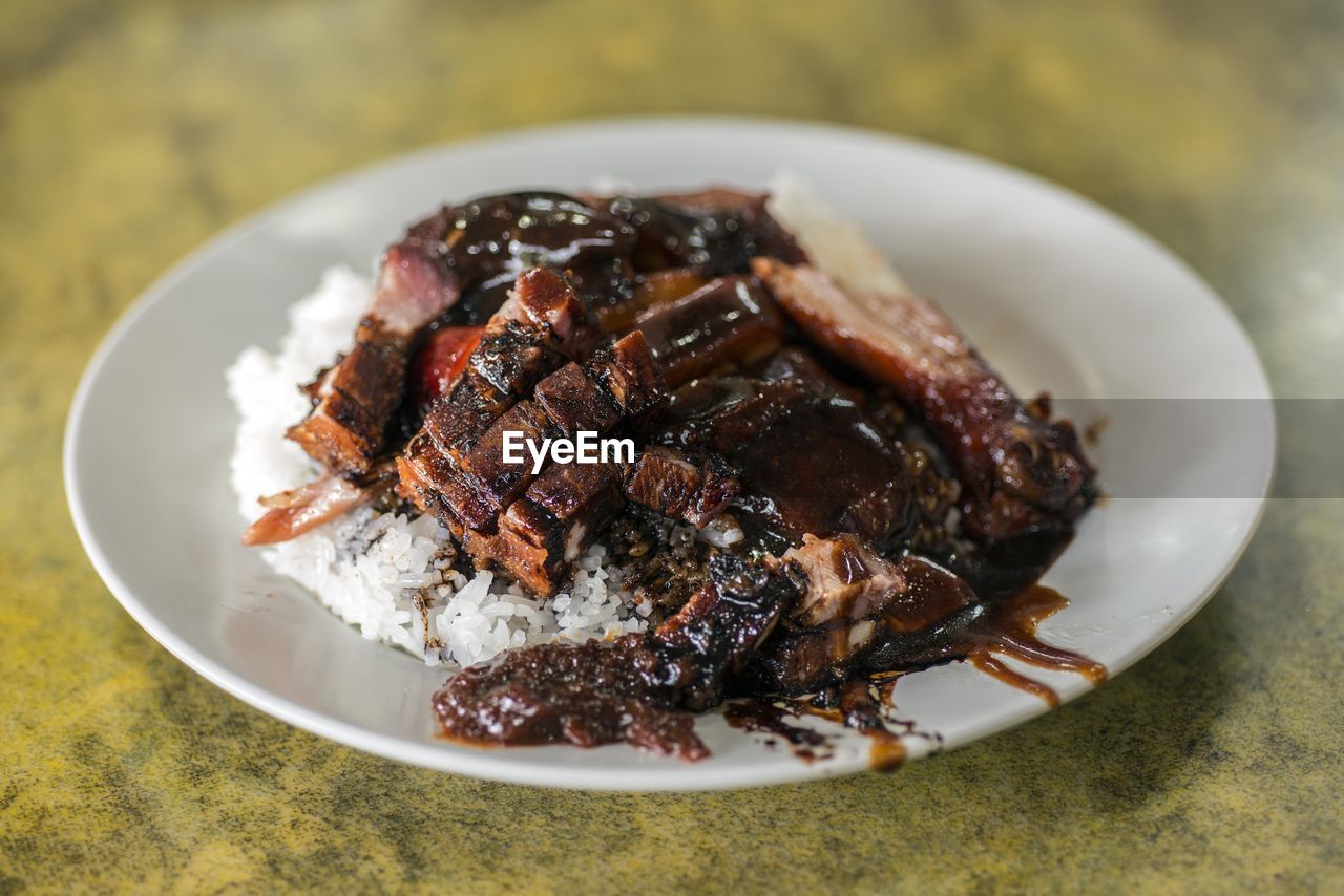 Close-up of roast pork with rice in plate on table