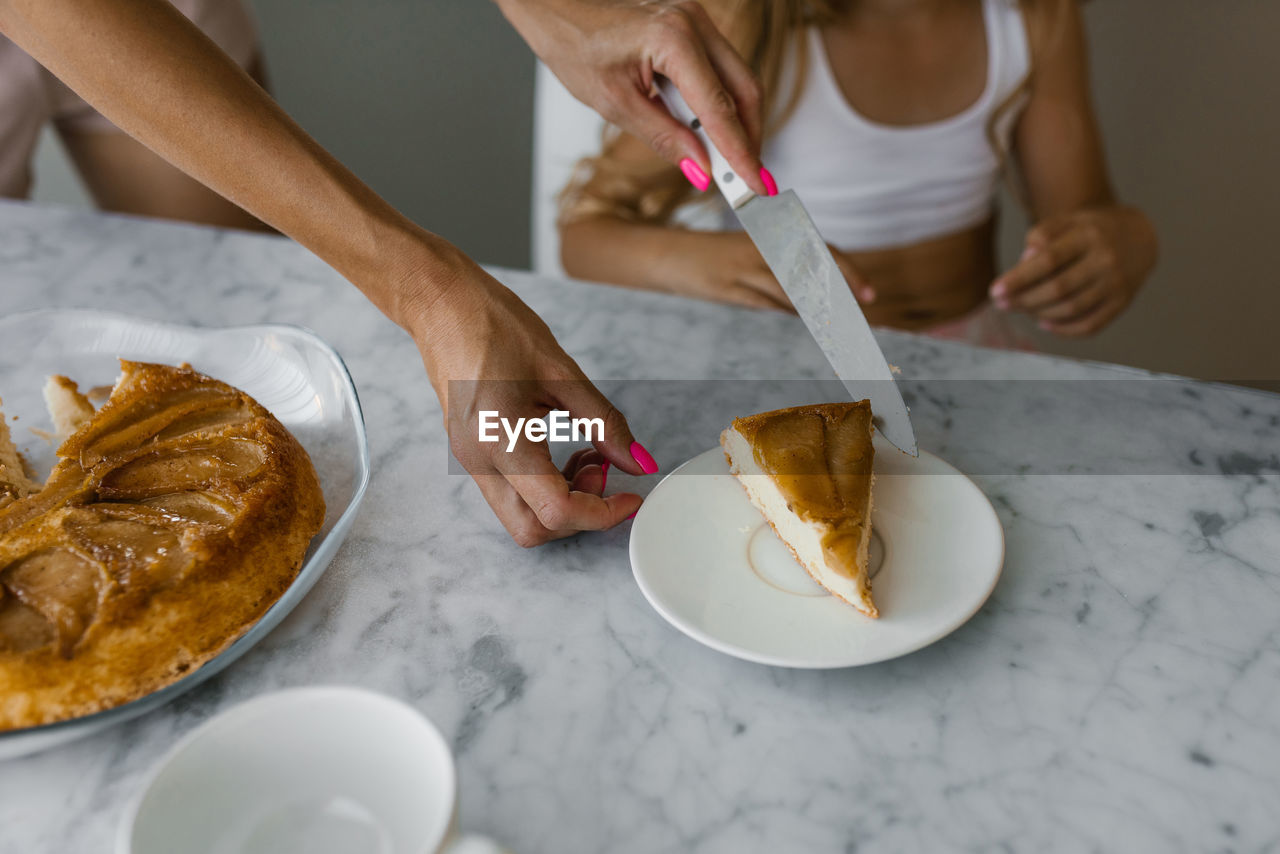 Close up of mother's hands putting a piece of apple pie on a plate for breakfast in the morning