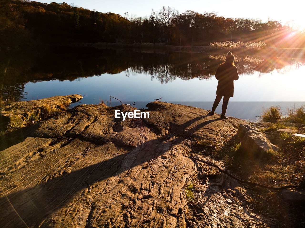 REAR VIEW OF MAN STANDING ON LAKE