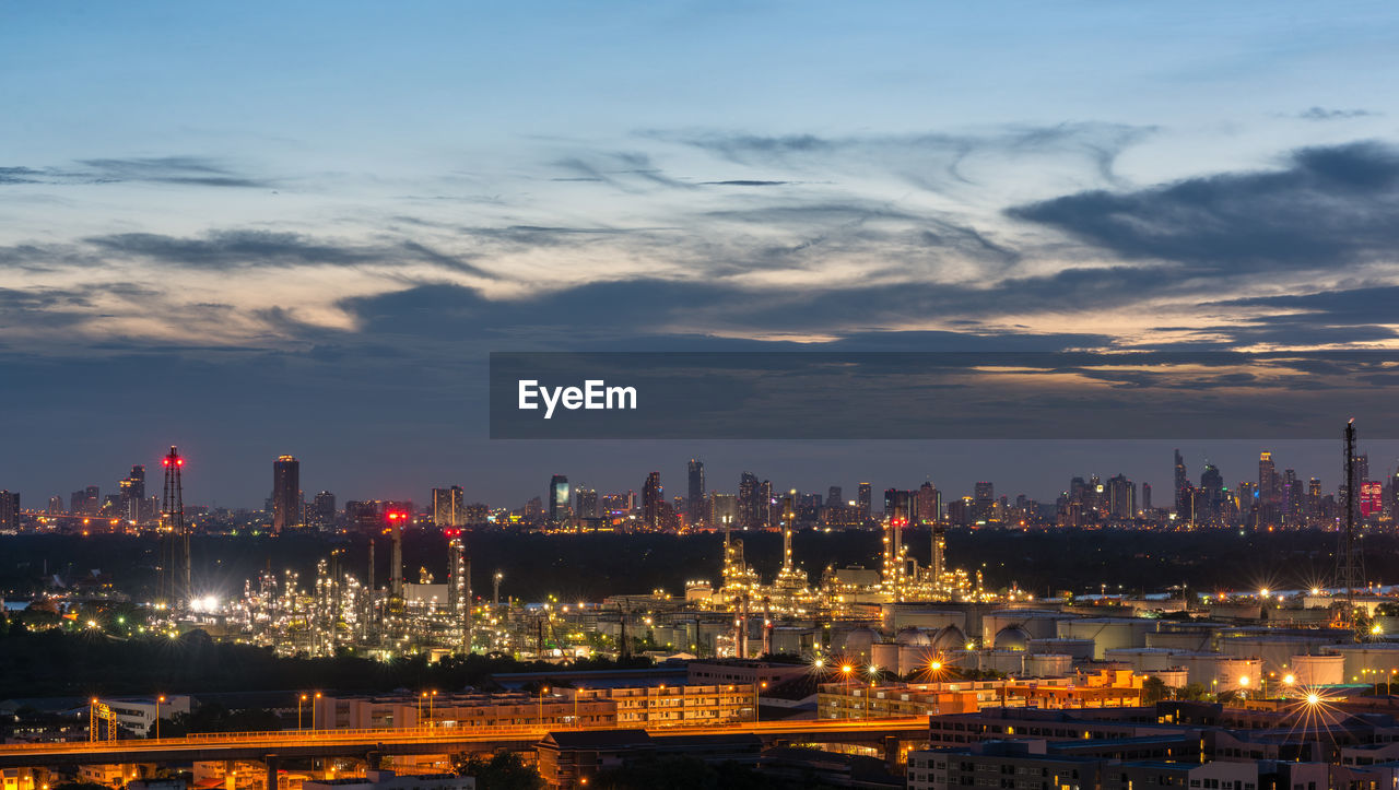 ILLUMINATED CITY BY BUILDINGS AGAINST SKY AT NIGHT