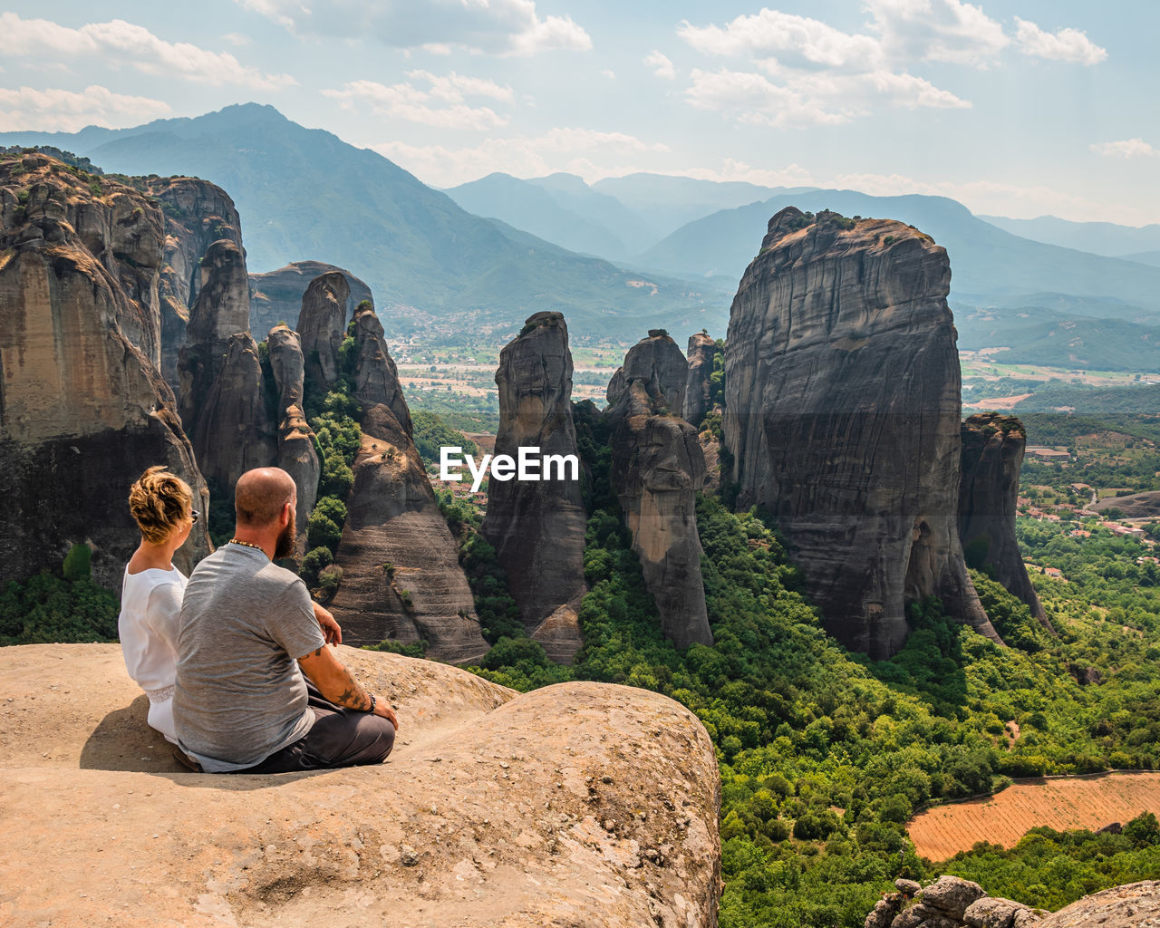 Couple sitting facing with panorama at meteora in greece