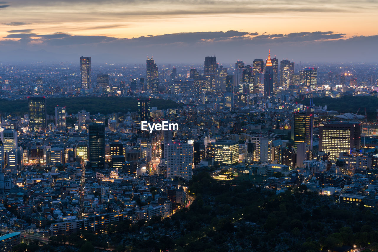 Illuminated cityscape against sky during sunset