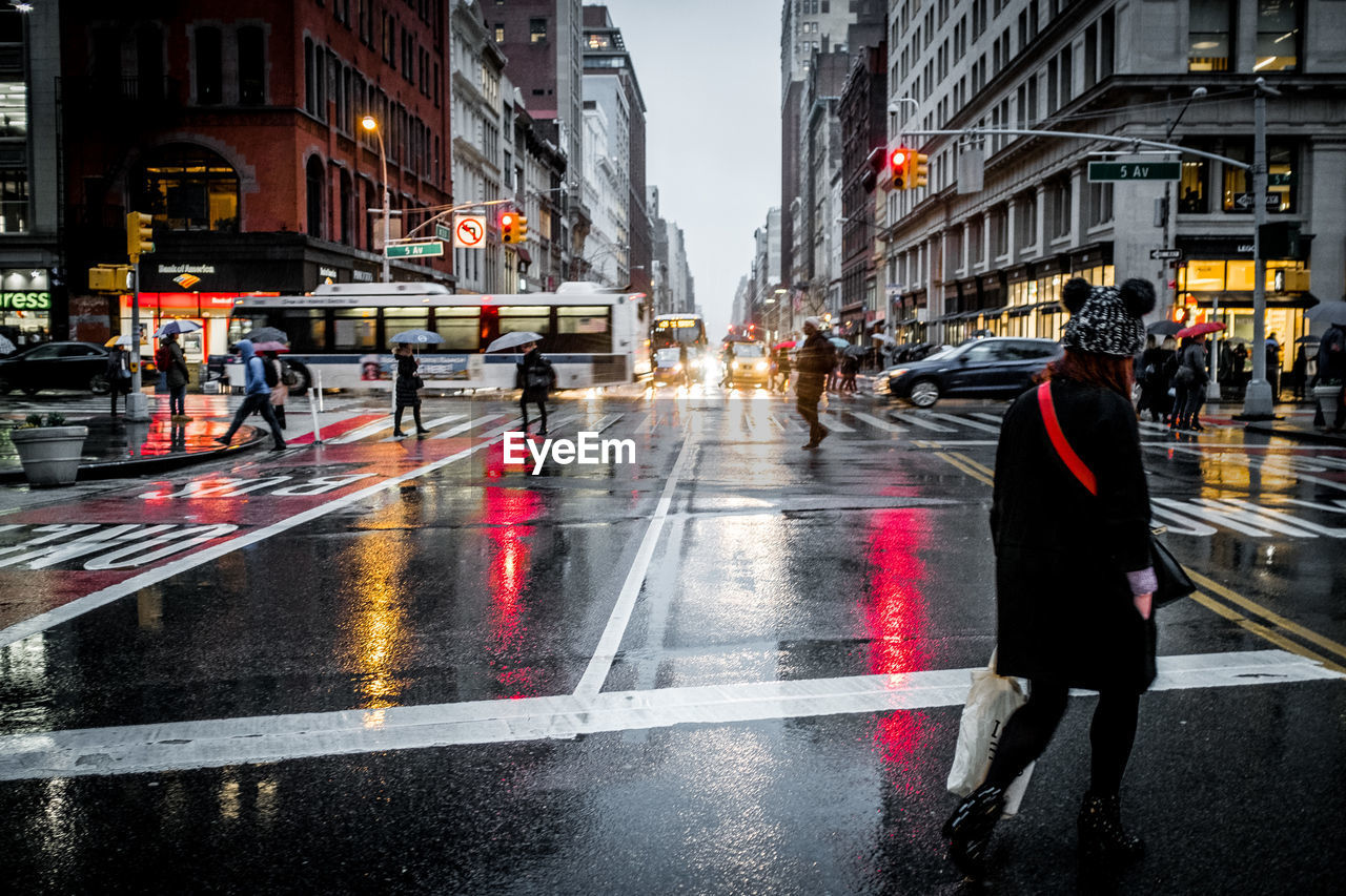 People walking on wet city street at dusk during rainy season