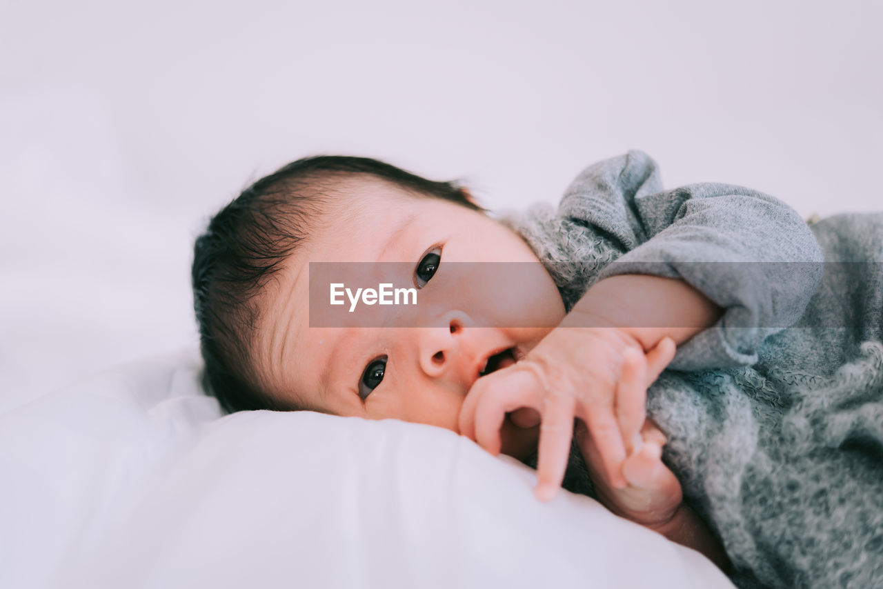 Close-up of cute baby boy lying on bed