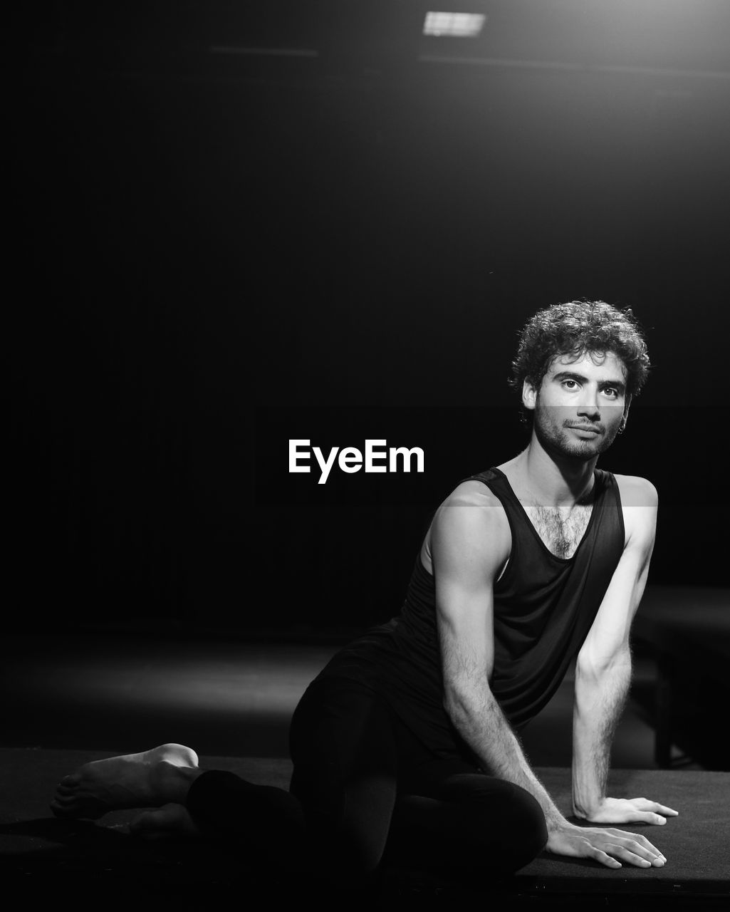 PORTRAIT OF YOUNG MAN LOOKING AWAY WHILE SITTING IN BLACK BACKGROUND