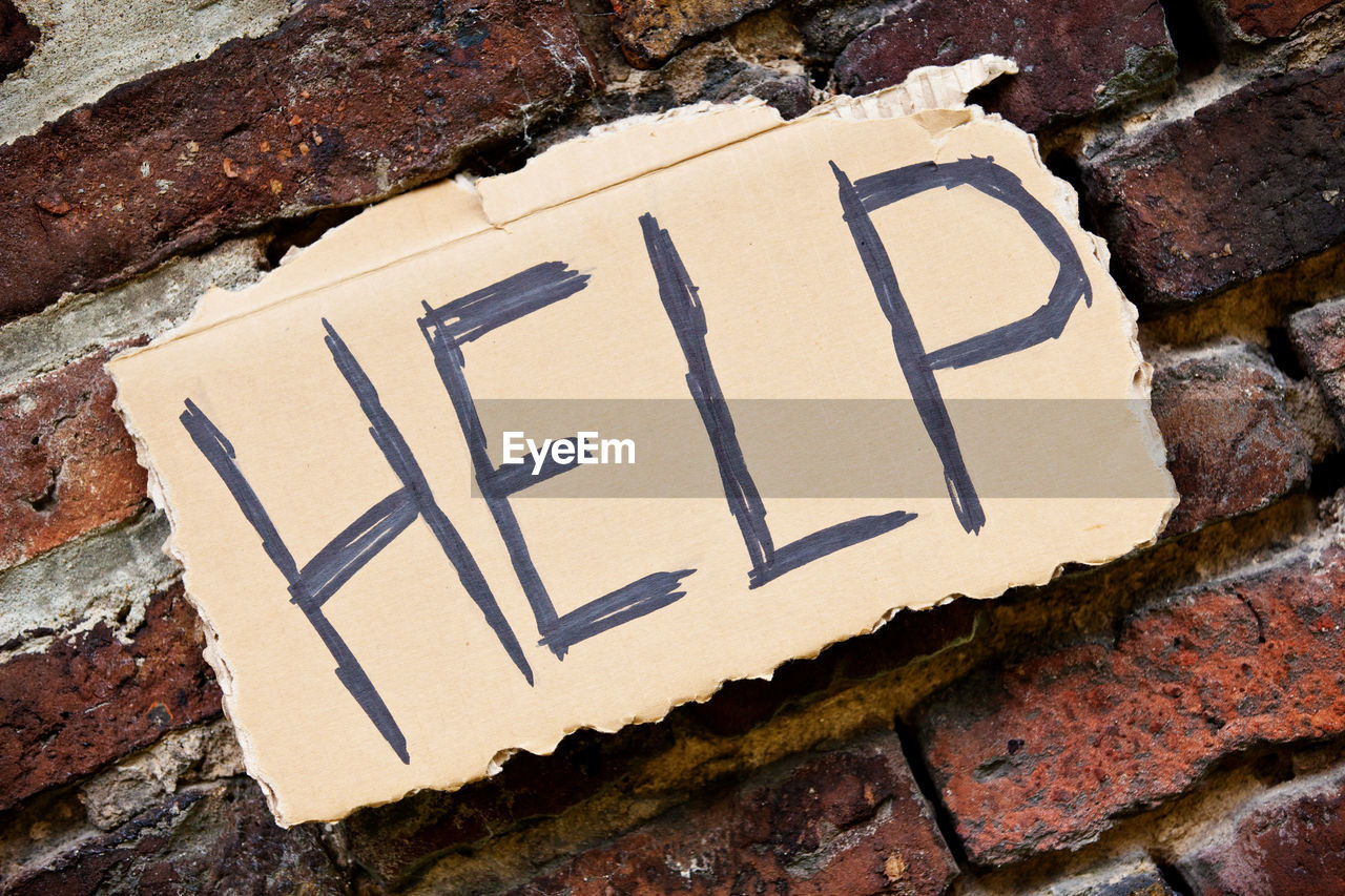 Close-up of help text on brick wall