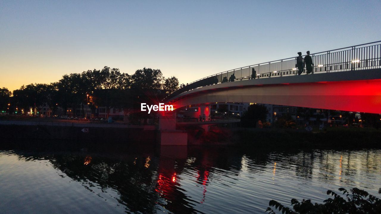 Silhouette bridge over river against sky at night