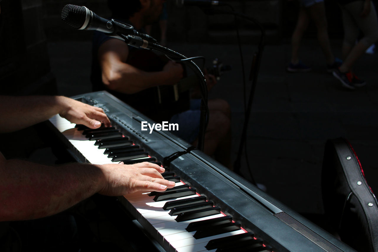 Cropped hand of man playing piano by microphone