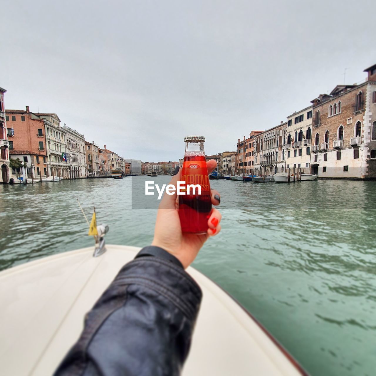 MAN HOLDING BOAT IN CANAL BY BUILDINGS IN CITY