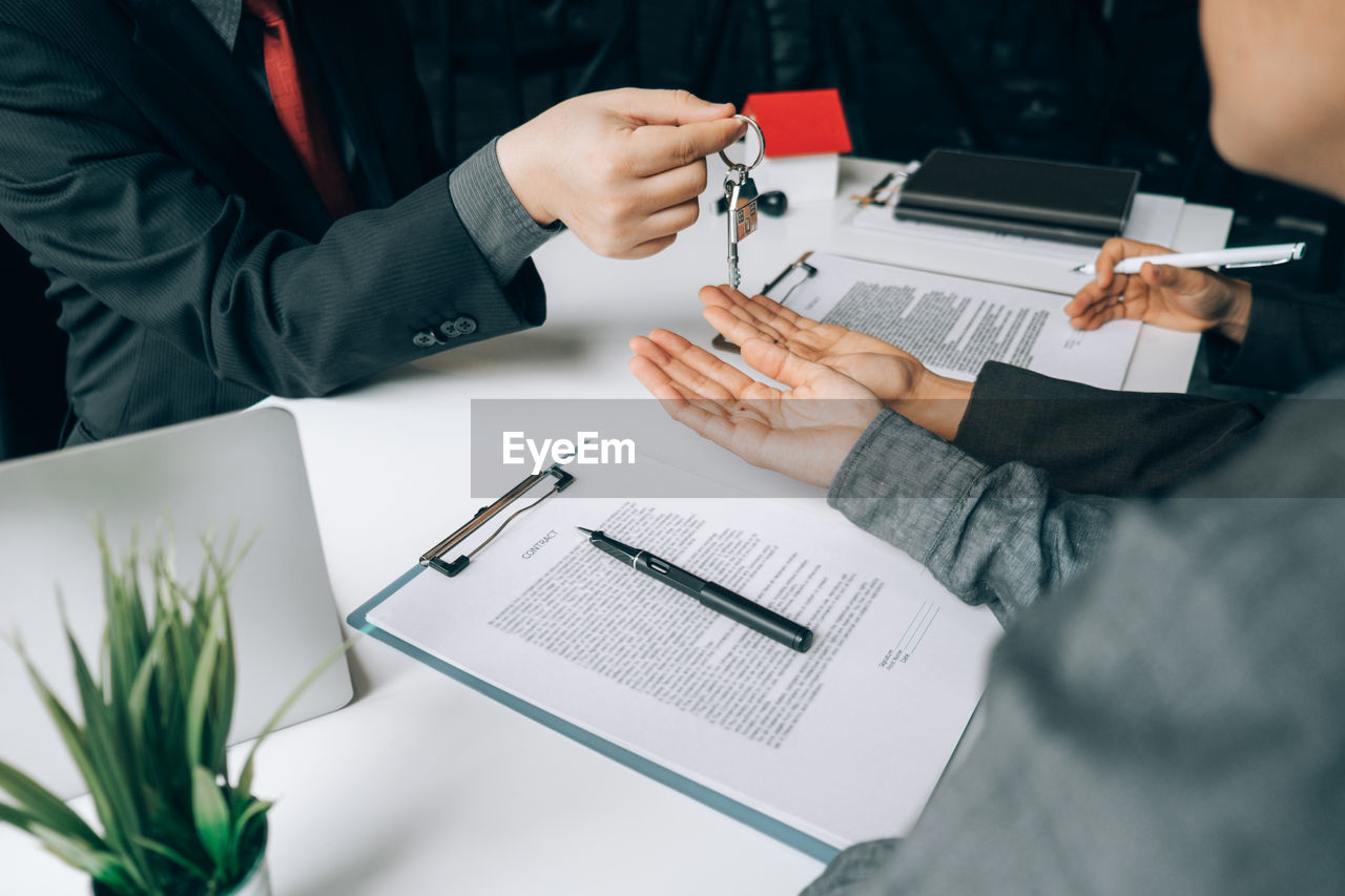 Midsection of lawyer giving keys to people