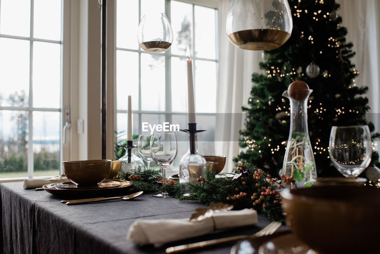 Tall lit candle on a decorated festive dinner table at christmas