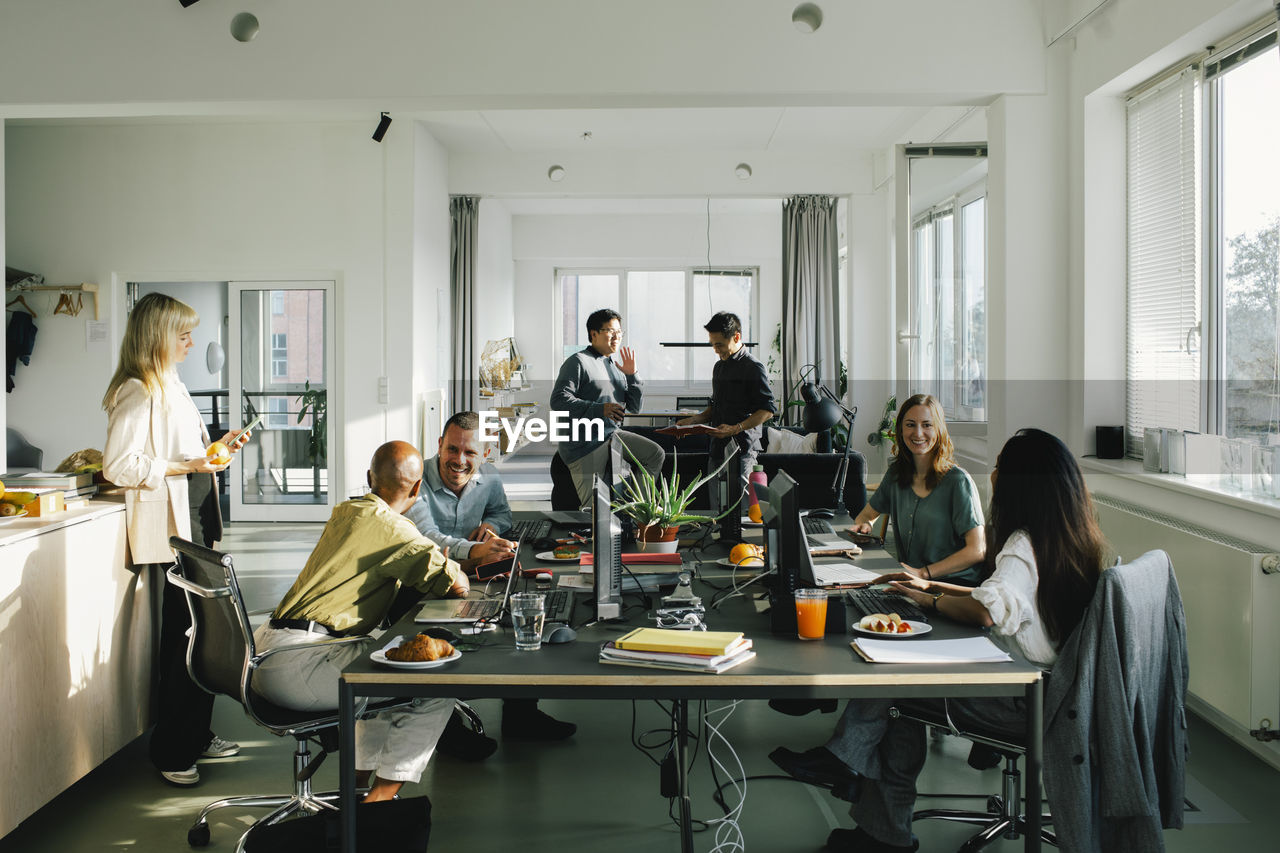 Multiracial male and female business colleagues communicating with each other at office