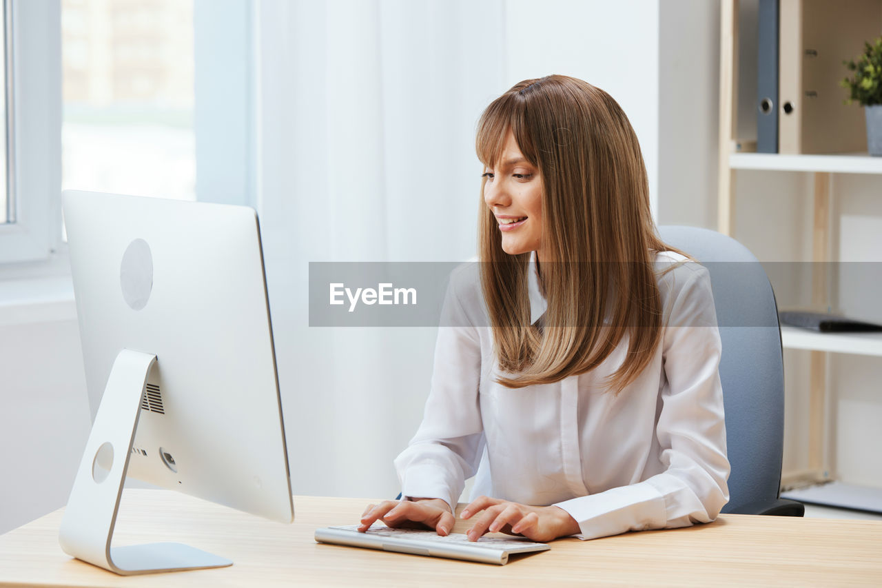 young woman using laptop at desk in office