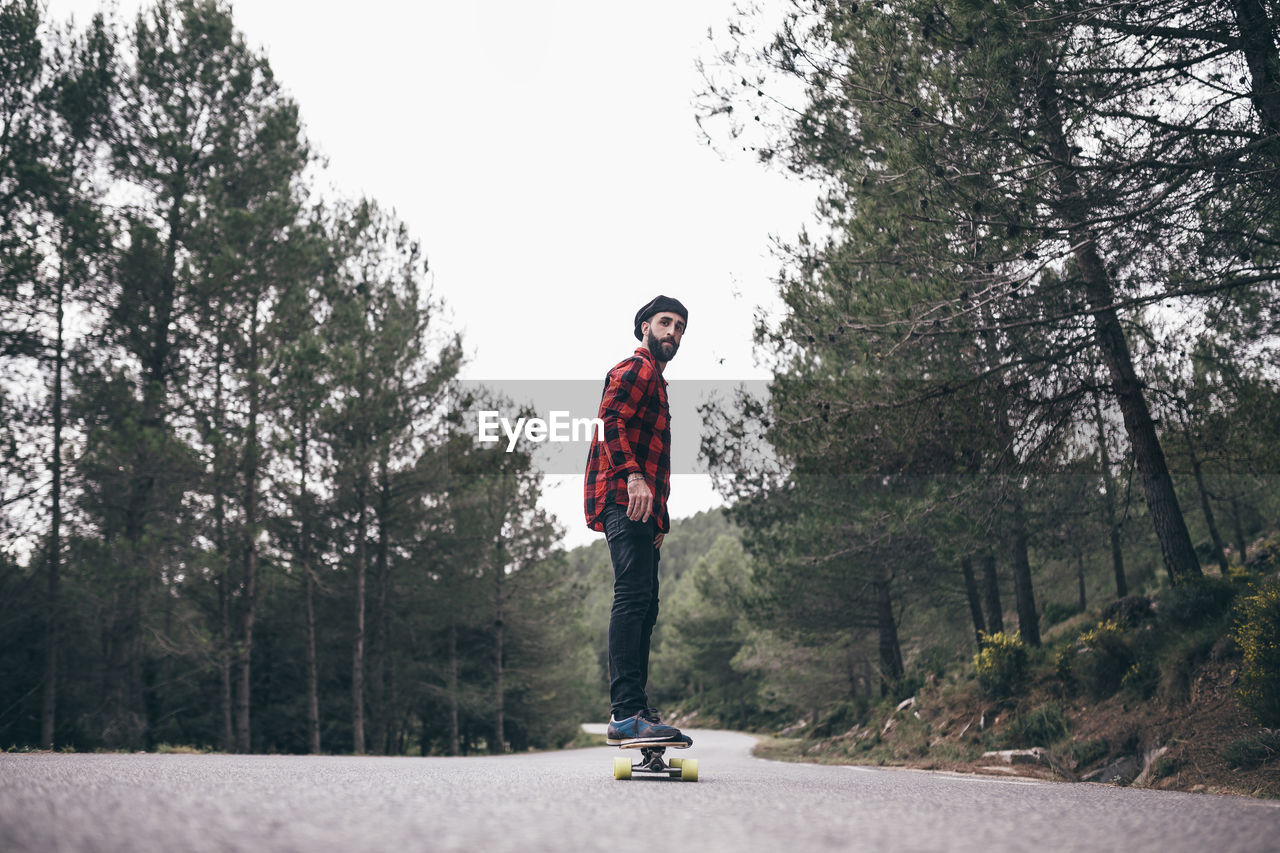 Man skateboarding on road amidst trees