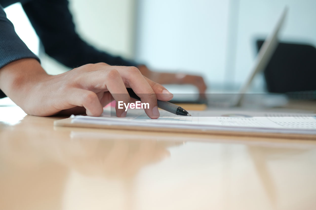 Cropped hands of businessman analyzing data at table in office 