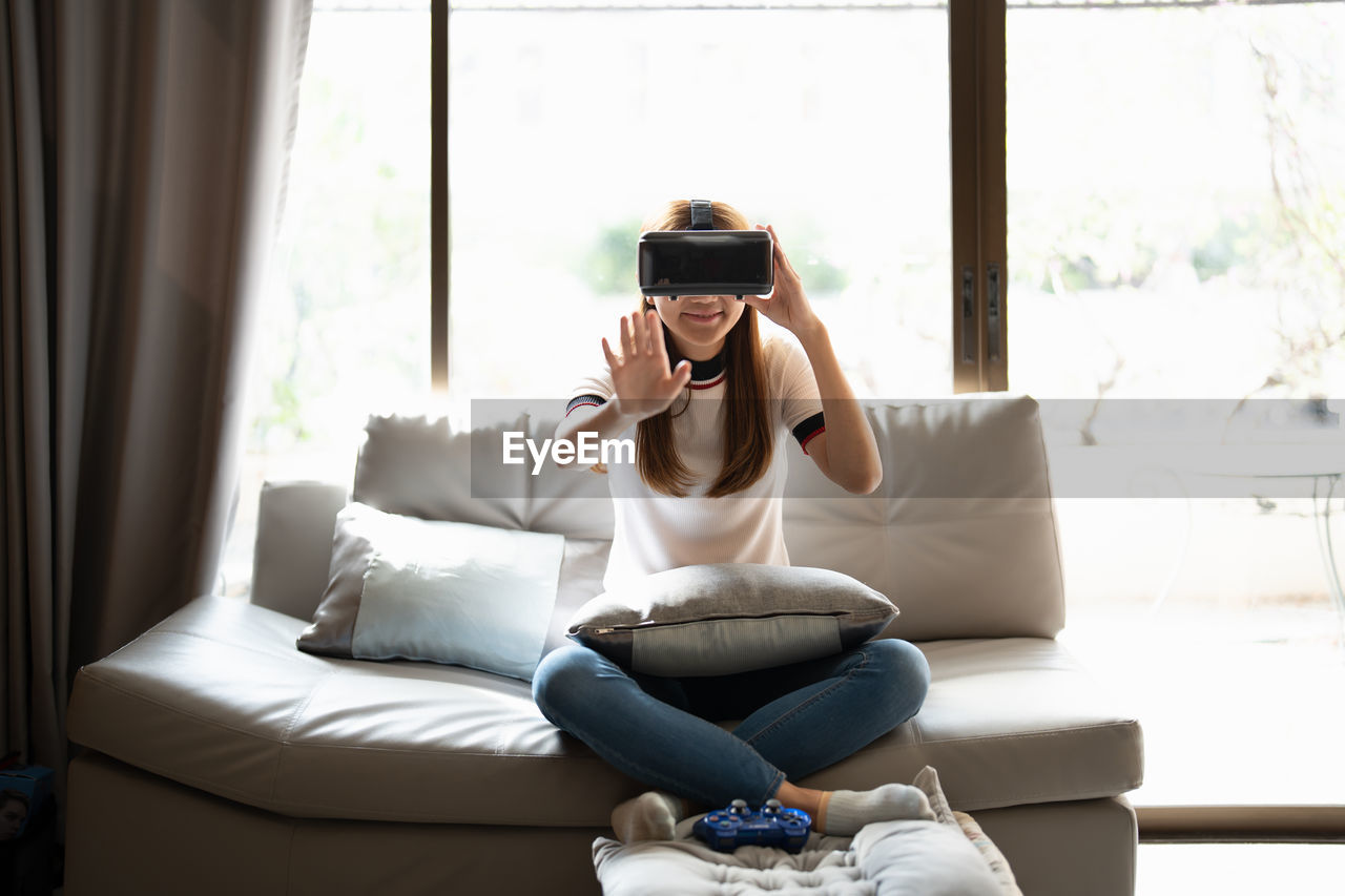 Woman wearing virtual reality headset while sitting at home