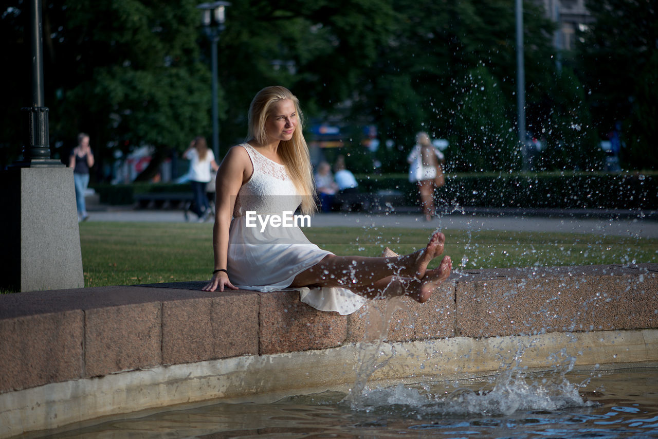 Woman dangling legs in swimming pool