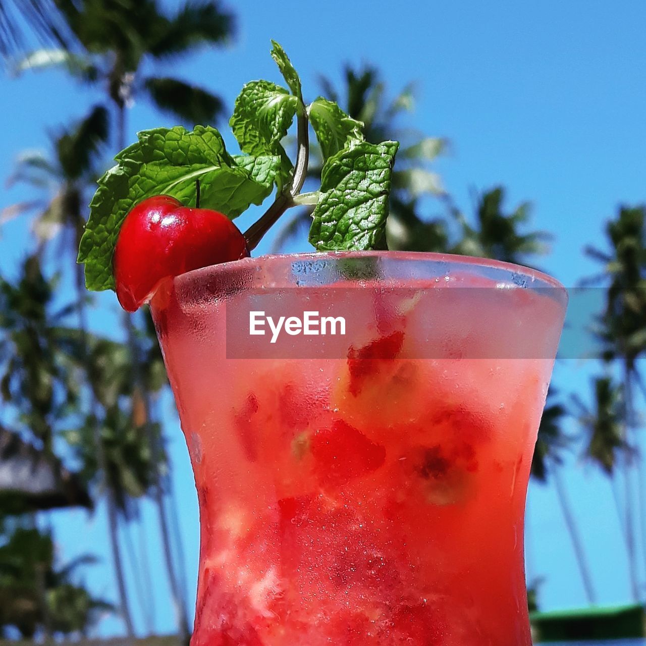 Close-up of red drink against trees