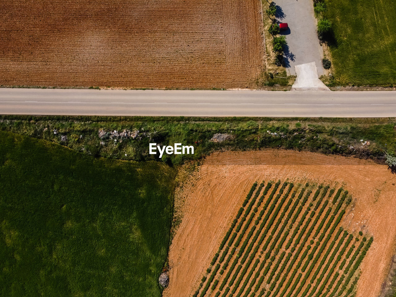 Aerial top drone view of road amidst farmland 