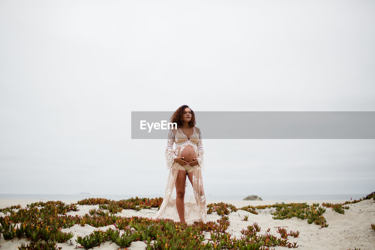 Young pregnant woman posing on beach