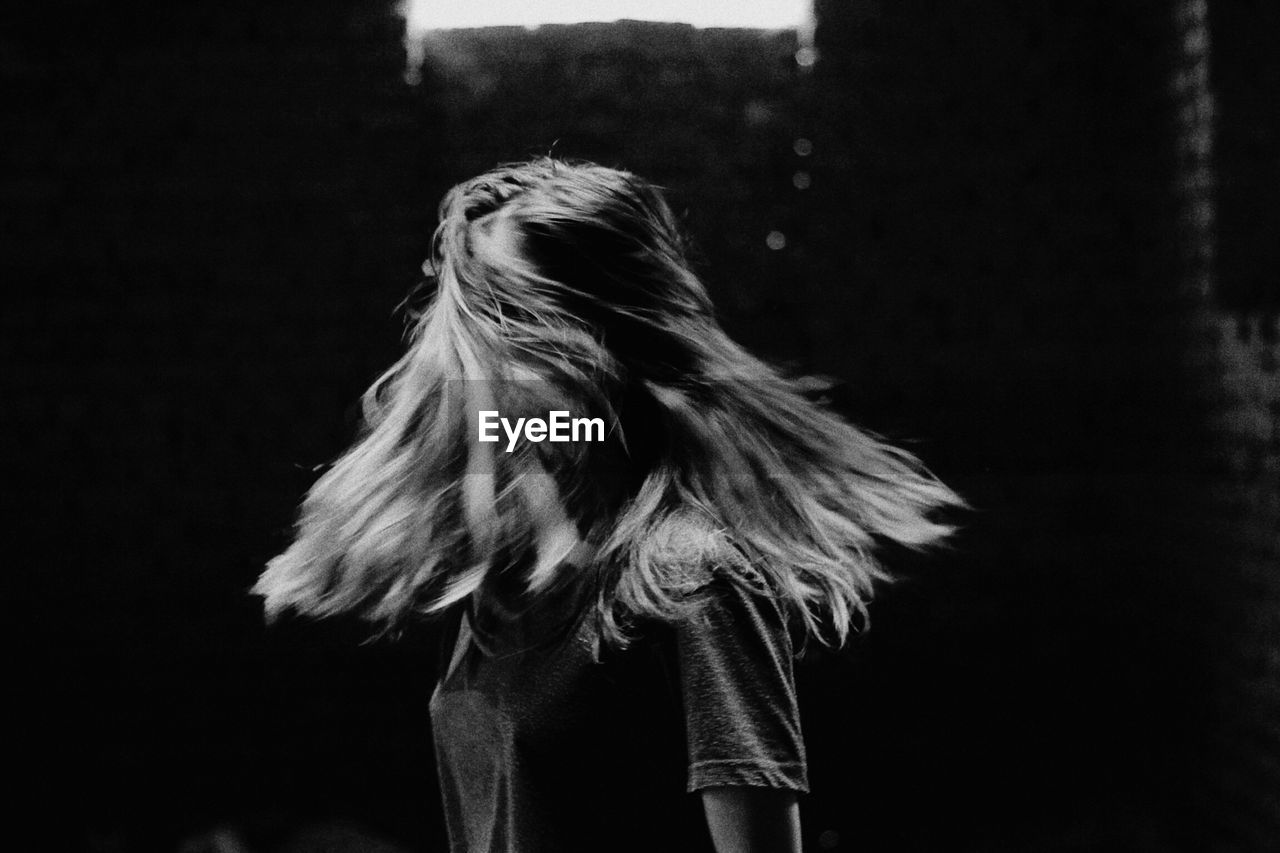 Young woman shaking head while standing outdoors at night