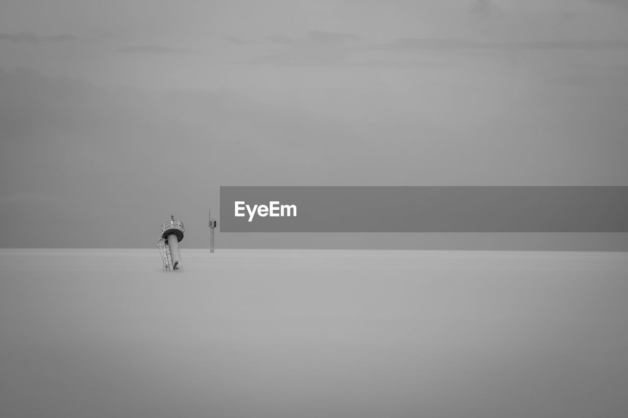 MAN STANDING AT SEA AGAINST SKY