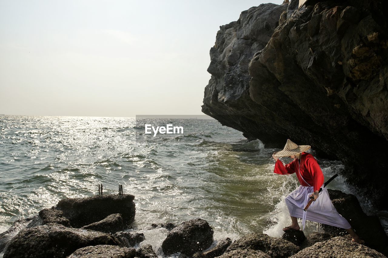 Asian woman with traditional clothing standing on seashore