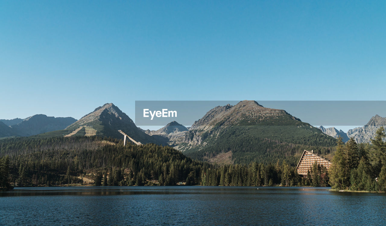 Scenic view of lake and mountains against clear blue sky