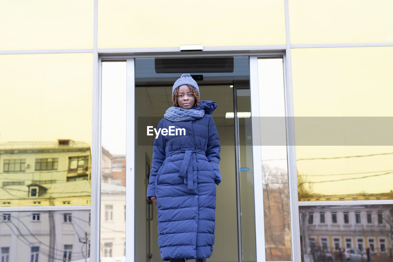 Portrait of woman standing by entrance of building