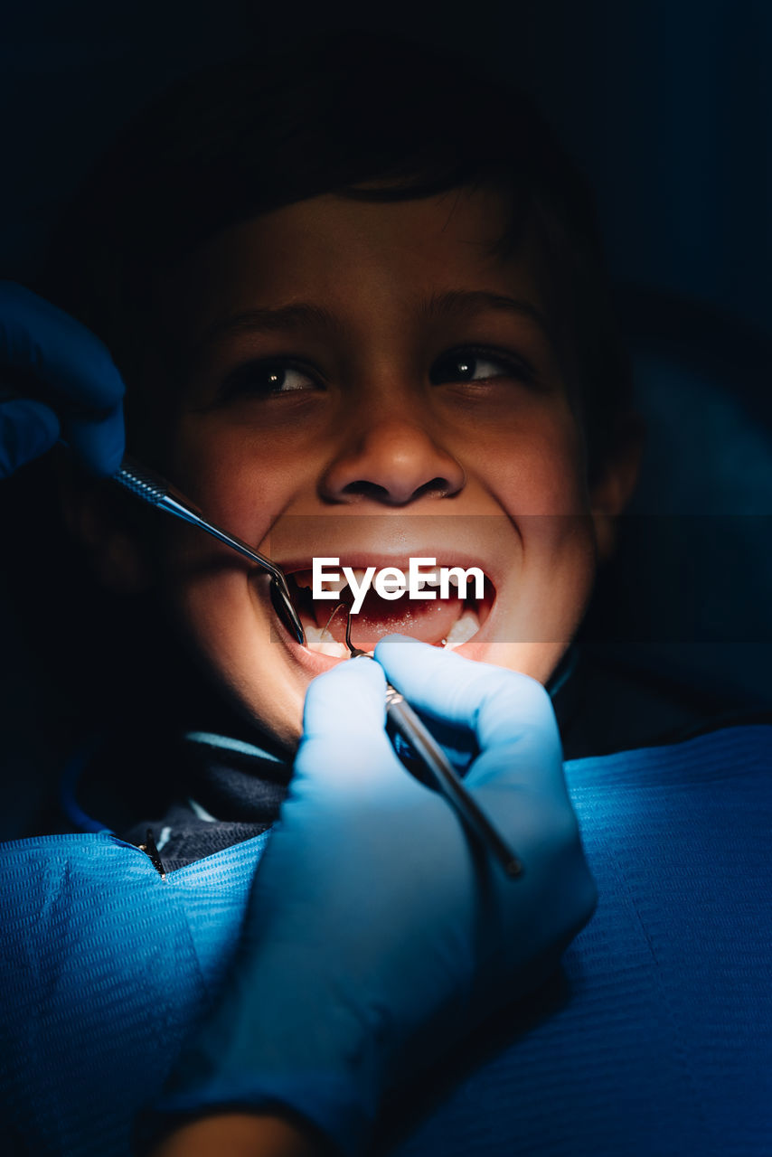 Dentist operating cheerful boy in medical clinic