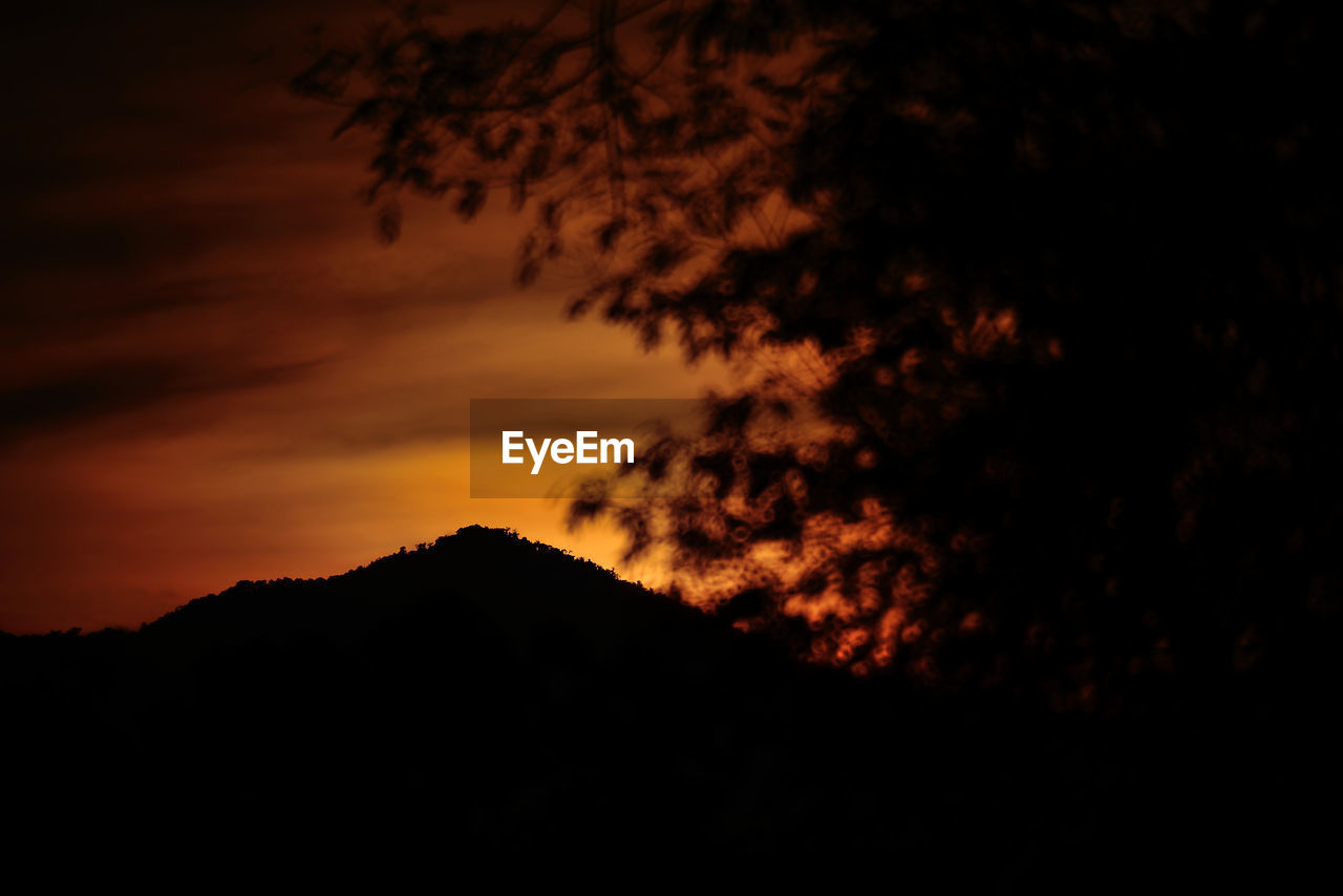 SILHOUETTE OF MOUNTAIN AGAINST DRAMATIC SKY