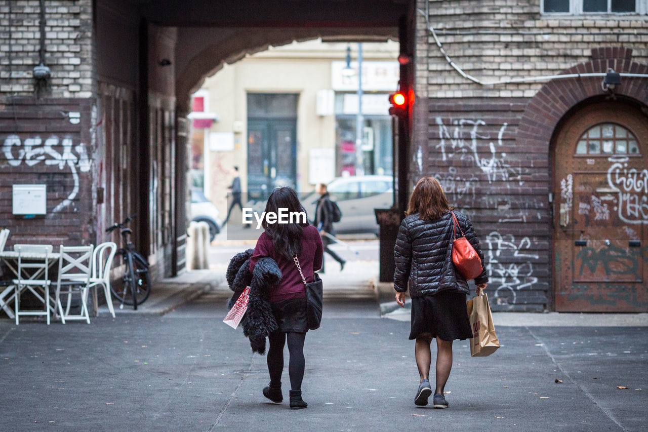 Rear view of women walking on street towards buildings