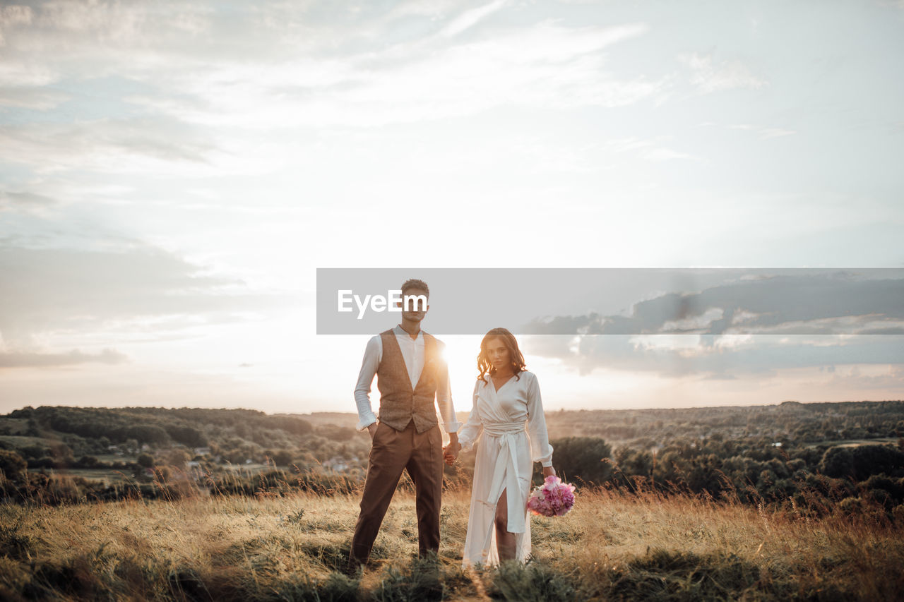 Full length of couple on field against sky