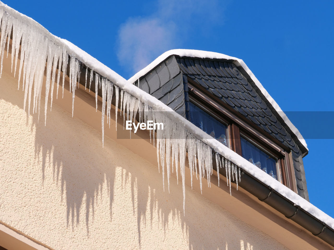 Low angle view of building against blue sky, icicles on a house 